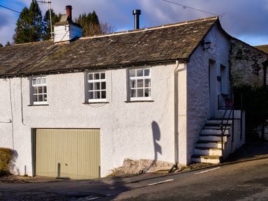 A white building with three windows a garage door and external stairs at Barn End in Ambleside