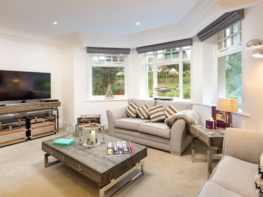 A living room with two sofas a wooden coffee table a television and windows at Skyfall in Bowness