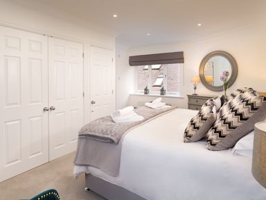 A bedroom with a large bed pillows bedside table lamps and a round mirror at Skyfall in Bowness