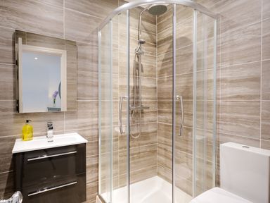 A bathroom with a glass shower enclosure a sink with a mirror above and a toilet at Skyfall in Bowness
