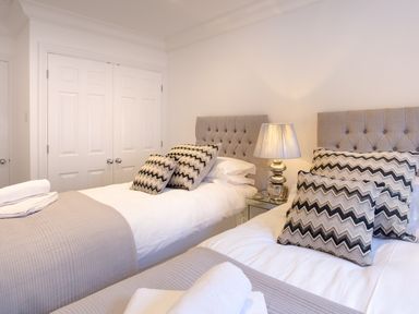 A bedroom with two single beds a bedside table and a lamp at Skyfall in Bowness