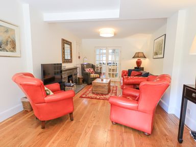 A living room with red armchairs wooden coffee table and fireplace at Rowan Cottage in Grasmere