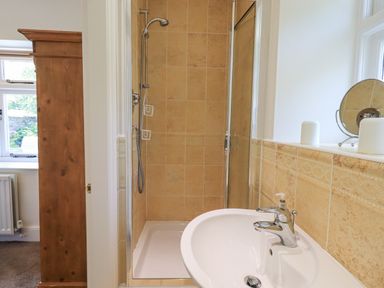 A bathroom with a shower enclosure and a sink with a faucet at Rowan Cottage in Grasmere