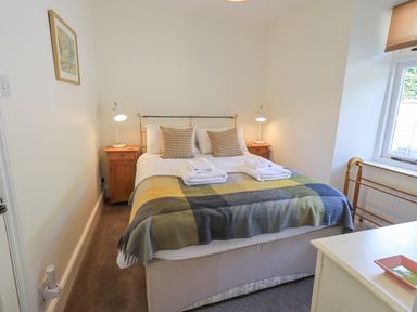 A bedroom with a double bed two bedside tables with lamps and a window at Rowan Cottage in Grasmere