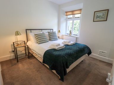 A bedroom with a double bed bedside tables lamps and a window at Rowan Cottage in Grasmere