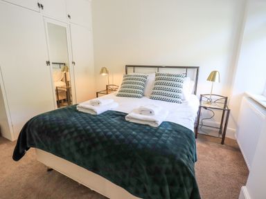 A bedroom with a double bed two bedside tables with lamps and built-in wardrobes at Rowan Cottage in Grasmere