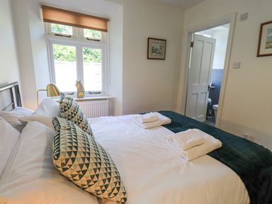 A bedroom with a double bed pillows and folded towels at Rowan Cottage in Grasmere