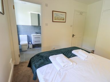 A bedroom with a bed and folded towels next to an ensuite bathroom at Rowan Cottage in Grasmere