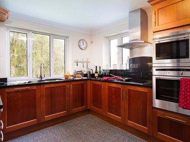 A kitchen with wooden cabinets black countertops and stainless steel appliances at Beech View in Ambleside