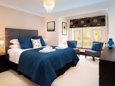 A bedroom with a bed blue bedding two chairs and a window at Beech View in Ambleside