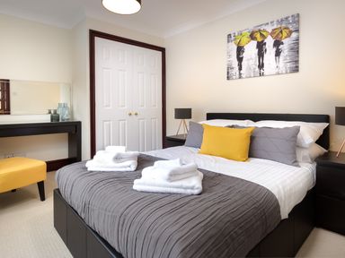 A bedroom with a bed linens and towels bedside tables lamps and a painting at Beech View in Ambleside