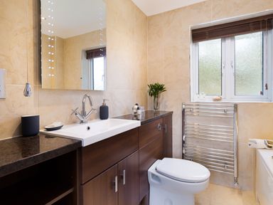 A bathroom with a sink a mirror a toilet and a window with blinds at Beech View in Ambleside