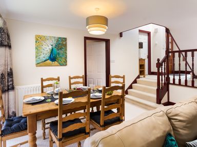 A dining area with a wooden table and chairs set for a meal next to a staircase at Beech View in Ambleside