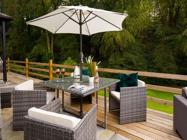 An outdoor patio with wicker chairs a table umbrella and drinks at Beech View in Ambleside