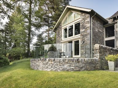 An outdoor area with a stone wall and glass railing at Take Five in Ambleside