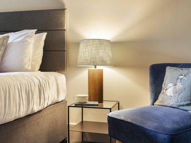 A bedroom with a bed, lamp, and armchair at Take Five in Ambleside