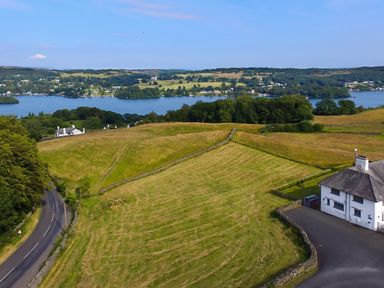 A rural landscape with a road a house fields trees and a lake in the background at Hawkrigg Farm Hawkshead