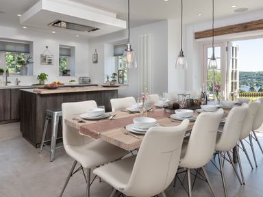 A dining area with a wooden table set for twelve and a kitchen with an island and stools at Hawkrigg Farm in Hawkshead
