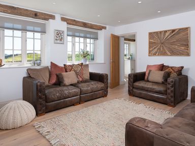 A living room with leather sofas and a woven rug at Hawkrigg Farm in Hawkshead