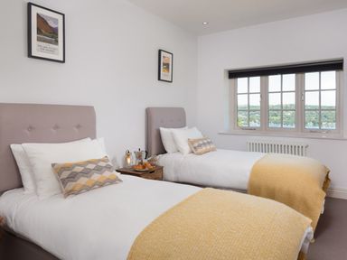 A bedroom with two single beds side by side with patterned pillows and yellow blankets at Hawkrigg Farm in Hawkshead