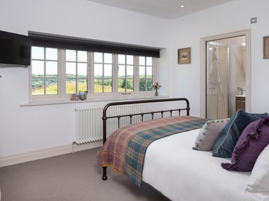 A bedroom with a metal bed frame and pillows next to a window and an ensuite bathroom at Hawkrigg Farm in Hawkshead
