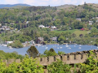 A view of a lake with boats and houses surrounded by trees and hills at Hawkrigg Farm in Hawkshead