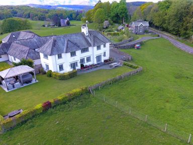 A white house with a garden and patio and a gazebo in a rural area with trees and fields at Hawkrigg Farm in Hawkshead