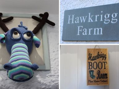 A knitted blue and striped moose head on a wall a slate sign with Hawkrigg Farm text and a wooden sign saying Hawkrigg Boot Room Please Remove Footwear at Hawkrigg Farm in Hawkshead
