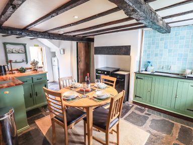 A kitchen with a wooden dining table set for four and green cabinets at Blease Garth in Threlkeld