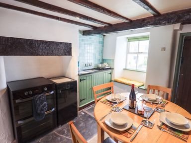 A kitchen with a wooden dining table set for four and appliances at Blease Garth in Threlkeld
