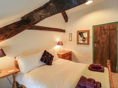 A bedroom with a double bed bedside tables lamps a wooden dresser and a wooden door at Blease Garth in Threlkeld
