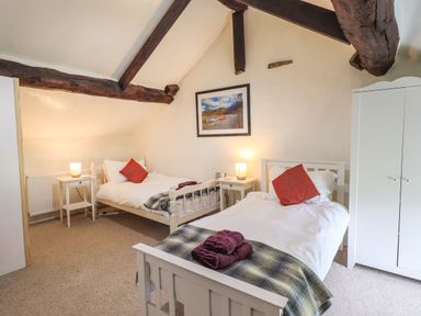 A bedroom with two single beds bedside tables lamps and a white wardrobe at Blease Garth in Threlkeld