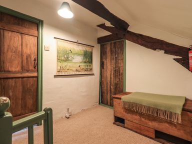 A hallway with wooden doors a bench and a wall chart at Blease Garth in Threlkeld