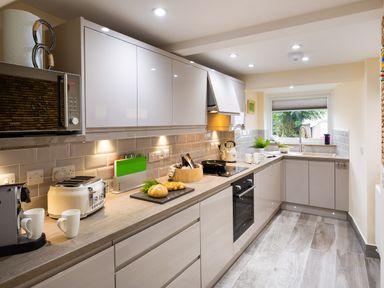 A kitchen with white cabinets toaster microwave and a window at Dovedale in Keswick