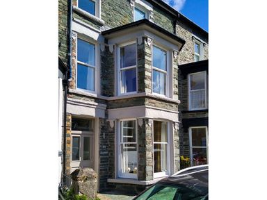 Exterior view of a stone house with bay windows and a front door labeled Dovedale in Keswick