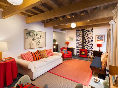 A living room with a white sofa red armchair and fireplace at Kentmere Hall Bank Barn in Kentmere