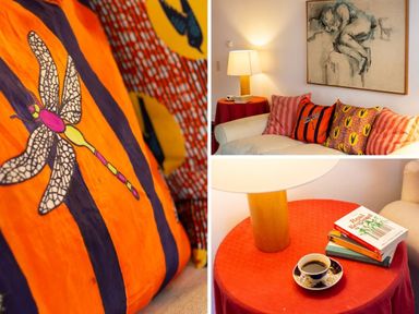 A living room with colorful patterned cushions on a sofa and a red round side table with books a lamp and a cup at Kentmere Hall Bank Barn Kentmere