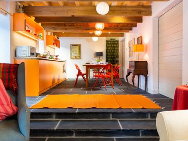 A kitchen and dining area with orange cabinets red chairs and wooden beams at Kentmere Hall Bank Barn in Kentmere