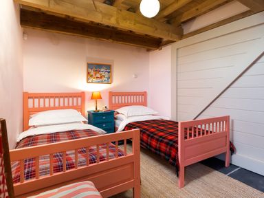 A bedroom with two single beds with plaid blankets a blue nightstand with a lamp and a painting on the wall at Kentmere Hall Bank Barn in Kentmere