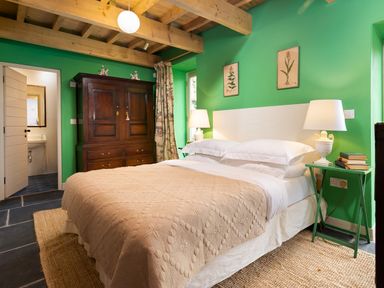 A bedroom with a bed bedside tables lamps an armoire and a door leading to a bathroom at Kentmere Hall Bank Barn in Kentmere