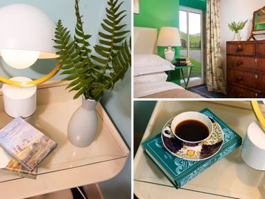 A bedroom with a bedside table holding a lamp a vase with fern leaves books and a cup of coffee at Kentmere Hall Bank Barn  Kentmere