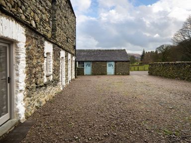 A stone building with white window frames and gravel yard at Kentmere Hall Bank Barn in Kentmere