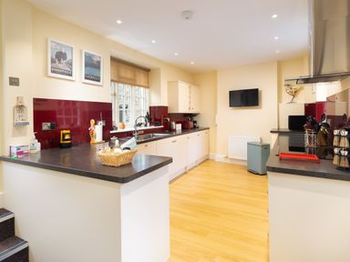 A kitchen with white cabinets dark countertops and wooden flooring at Scots Pine in Keswick