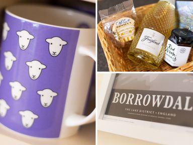 A mug with sheep faces a basket with prosecco fudge and red onion marmalade and a framed borrowdale print at Scots Pine in Keswick