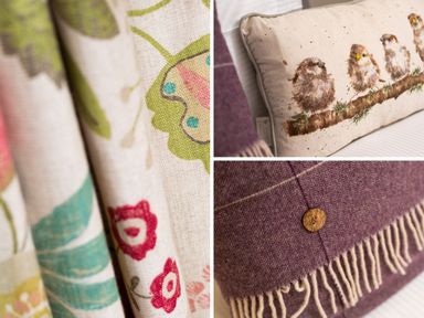 Close up of floral patterned curtains birds on a cushion and a fringed throw at Scots Pine in Keswick