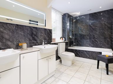 A bathroom with two sinks toilet bathtub with shower and a stool at Scots Pine in Keswick