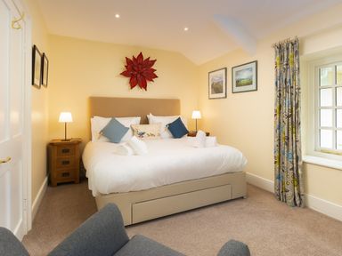 A bedroom with a double bed two bedside tables lamps wall art and a window with curtains at Scots Pine in Keswick
