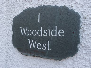 A property sign with number and name at Woodside West in Bowness