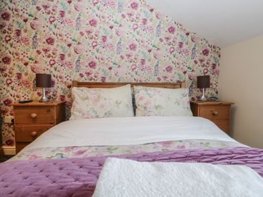 A bedroom with a bed and nightstands at Woodside West in Bowness