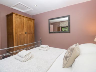 A bedroom with a bed and wardrobe at Corner Cottage in Troutbeck